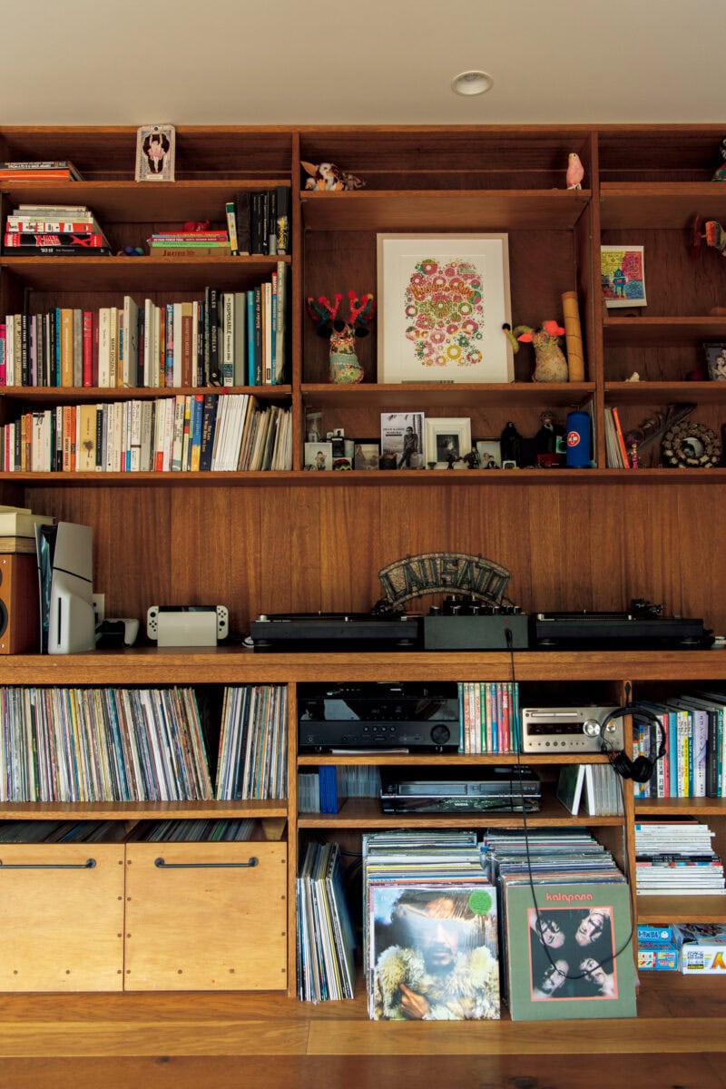 リノベの際に造りつけたオーク材のシェルフ。弟さんから譲り受けたターンテーブルを中心に、レコードや本、家族の趣味のグッズが並ぶ。 右上に飾ってあるのはハワイ在住のアーティスト「Jared Yamanuha」の切り絵作品。