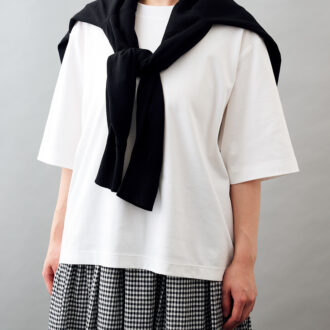 肩にかけた黒カーディガン¥2,990、ギンガムチェックのスカート¥4,990／ともに無印良品（無印良品 銀座）