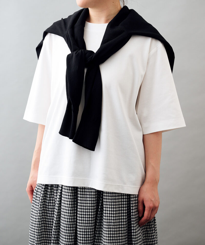肩にかけた黒カーディガン¥2,990、ギンガムチェックのスカート¥4,990／ともに無印良品（無印良品 銀座）