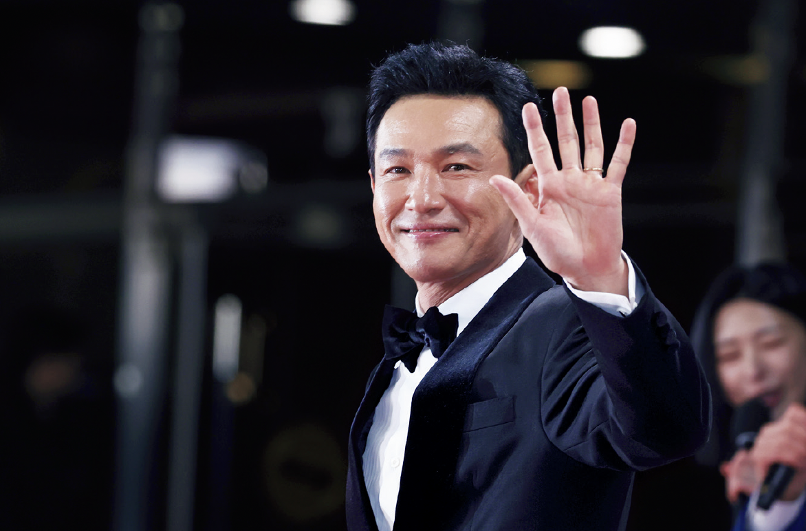 1970年生まれ。90年に『将軍の息子』で俳優デビュー後、映画『新しき世界』や『国際市場で逢いましょう『』ベテラン』など数々の話題作に出演。 『ハッシュ～沈黙注意報～』や『ナルコの神』などのドラマや舞台『マクベス』などでも活躍。 不倫する弁護士や破天荒な熱血刑事、悪徳市長など幅広い役柄をこなす。 『ソウルの春』では特殊メイクで劇的な変身を遂げ、新たな独裁者としてクーデターを決行するチョン・ドゥグァン保安司令官を怪演して話題に。 写真：YONHAP NEWS/アフロ