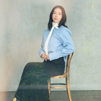 タイ付きシャツ￥88,000／エストネーション、中に着たニット￥39,600 ／コラム（ともにエストネーション）、スカート￥36,300／ロンハーマン、3連リング￥352,000／スピネリキルコリン（リトルリーグ インク）、シューズ￥198,000 ／ジェイエムウエストン（ジェイエムウエストン 青山店）